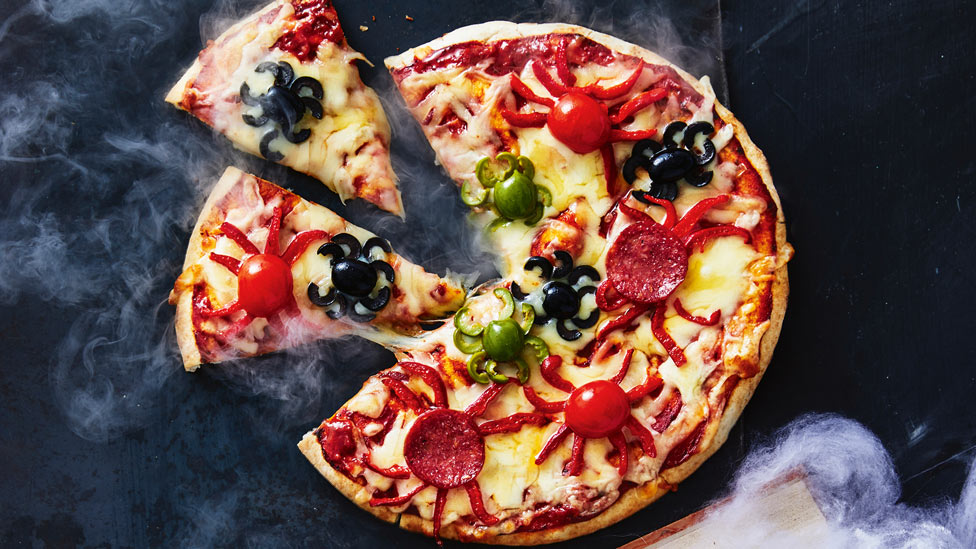 A pizza with spiders made of sliced tomato and oliver