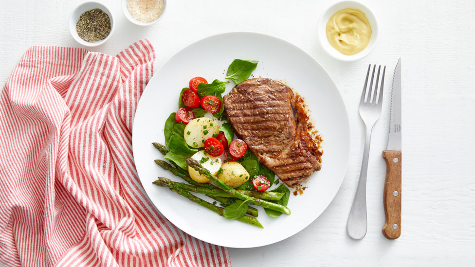 Steak with potato salad, tomato and asparagus