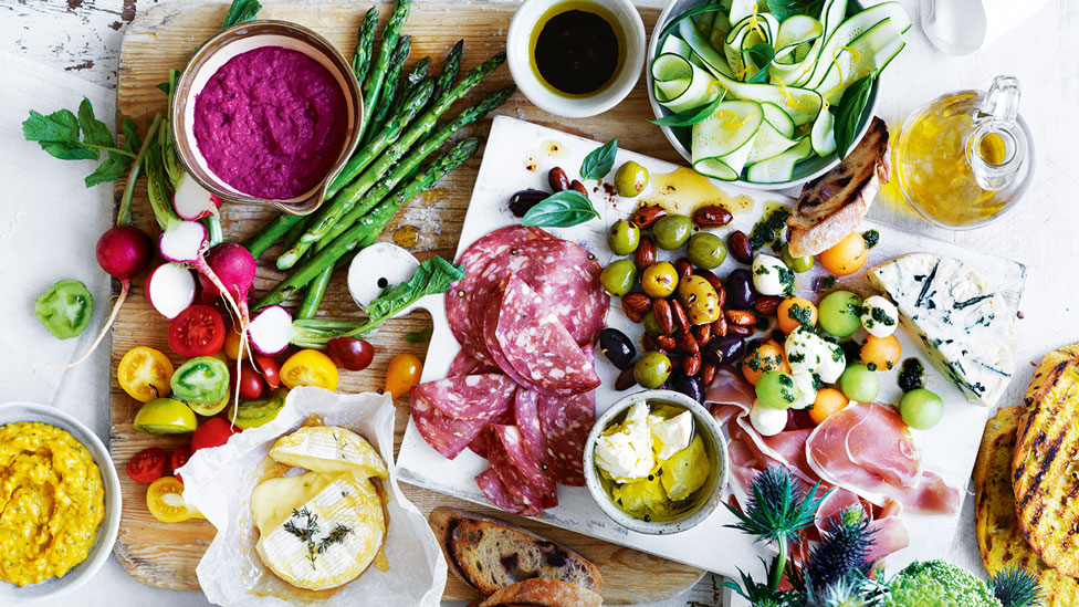 An antipasto platter with olives, baked brie and salads