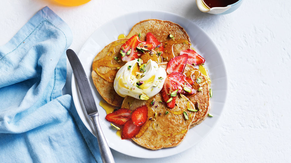 Banana and oat pancakes topped with strawberries and seeds