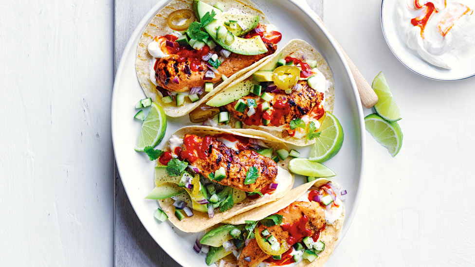 Four chicken tacos served with lime and sriracha