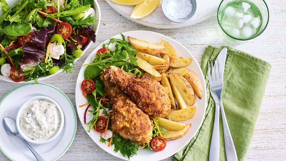 Two fried chicken drumsticks with homemade potato wedges and tartare sauce