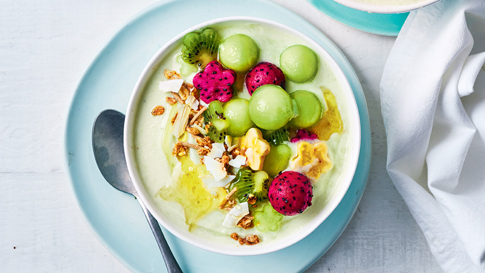 Green smoothie bowl topped with fruit and muesli 
