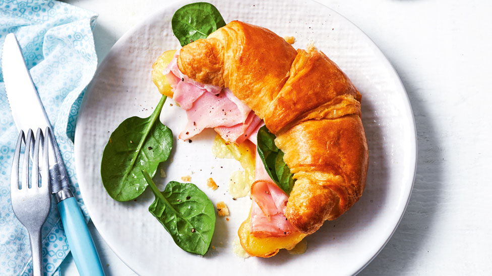 A ham and cheese croissant with spinach