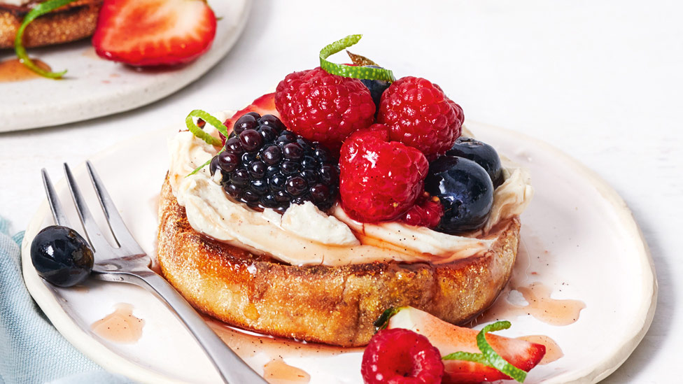 An english muffin with cream and marinated fruit on top