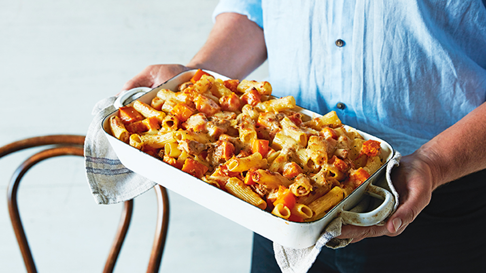 Tuna pasta bake made with roast pumpkin being held by a chef