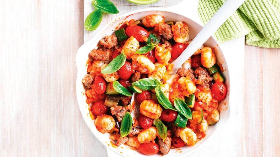 Sausage tomato and eggplant gnocchi in a bowl topped with basil leaves