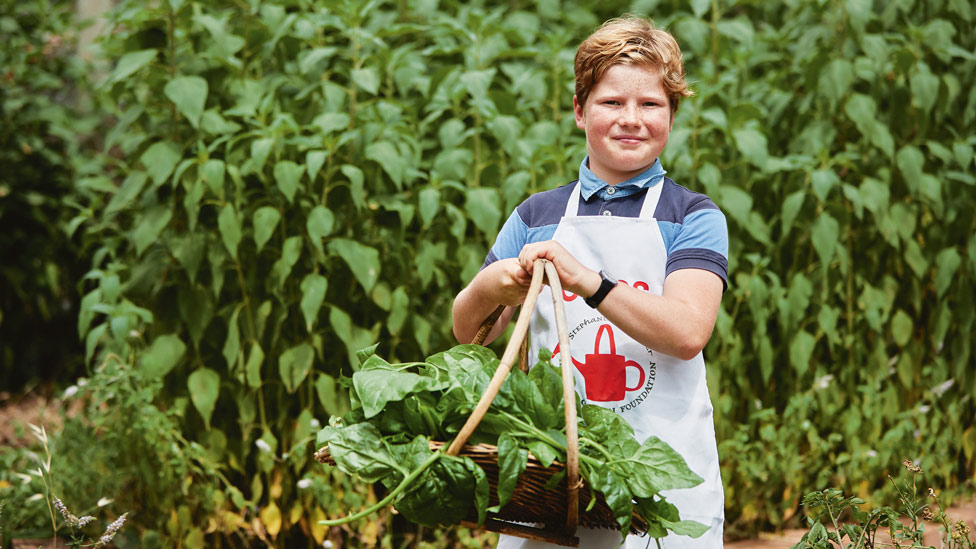 A child holding a basket of fresh produce