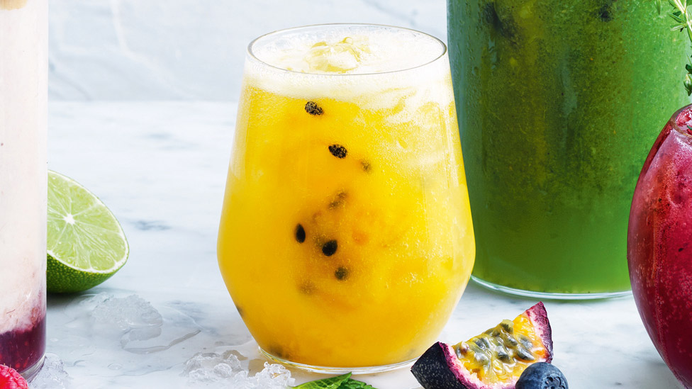 Passionfruit, mango and orange fizz top with ice and mint leavesa