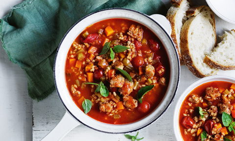 Two bowls of Italian sausage and barley soup served with toast