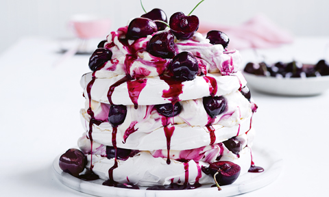 Three layers meringue and cherry torte topped with cherries
