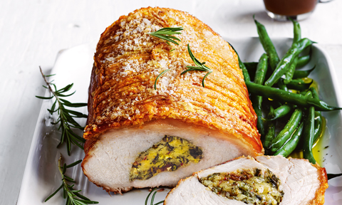 Roast pork with date and herb stuffing thickly sliced with green beans and gravy