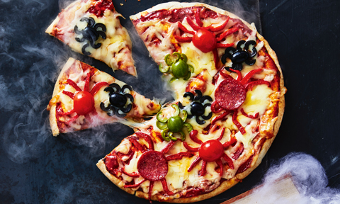 A pizza with spiders made of sliced tomato and oliver