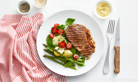 Steak with potato salad, tomato and asparagus