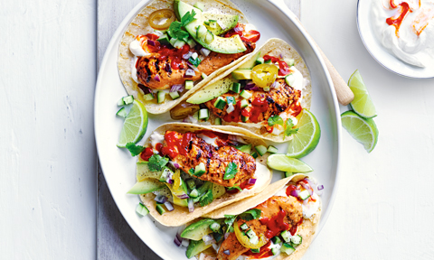 Four chicken tacos served with lime and sriracha