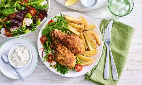 Two fried chicken drumsticks with homemade potato wedges and tartare sauce