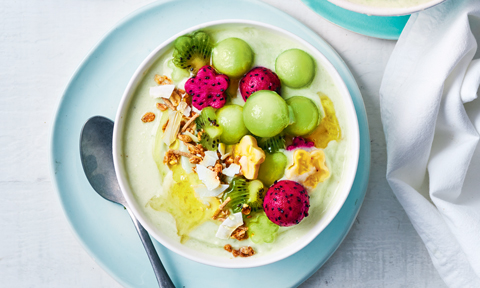 Green smoothie bowl topped with fruit and muesli 