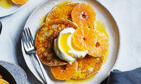 Lemon poppyseed pancakes topped with whipped cream and sliced mandarins