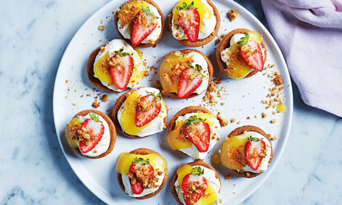 Mini cheesecake tarts served on a platter with strawberries on top