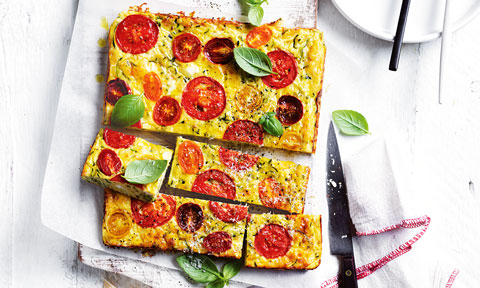 Cheese, tomato and zucchini slice cut in four sections and served on baking paper