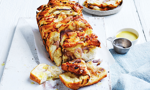 Whole loaf of cheesy onion pull-apart with dipping sauce on the side
