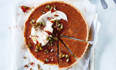 Whole pumpkin pie with two slices cut put and served with whipped cream on top
