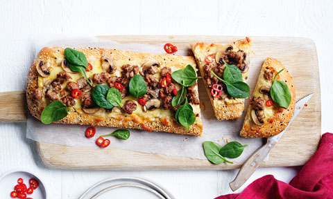 Sausage and mushroom pide served on a chopping board and cut into three sections