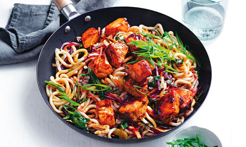 Teriyaki salmon portions served in a bowl with udon noodles and rocket on top