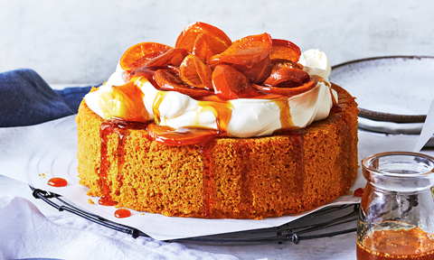 Whole mandarin and almond cake with whipped cream and oranges on top