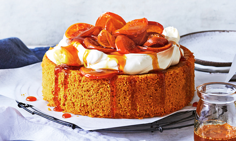 Whole mandarin and almond cake with whipped cream and oranges on top