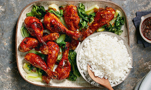 Sticky chicken drumsticks served with rice and greens