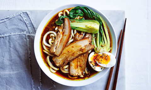 Japanese soup with noodles, pork, egg and bok choy served in a bowl with chop sticks