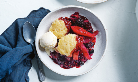 Pear, berry and white chocolate cobbler served in a bowl with a scoop of ice-cream on the top