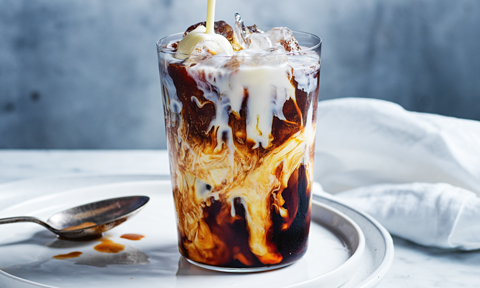 Vietnamese coffee served in a tall glass with a spoon on the side