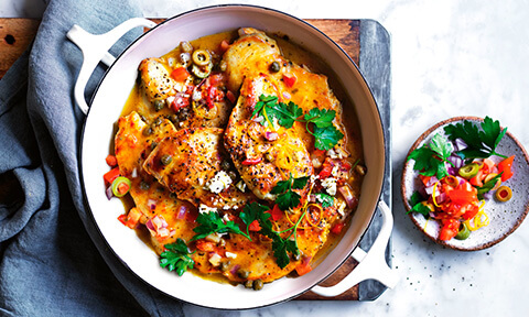 Italian-style lemon chicken served in a casserole dish with a parsley, tomato and olive garnish