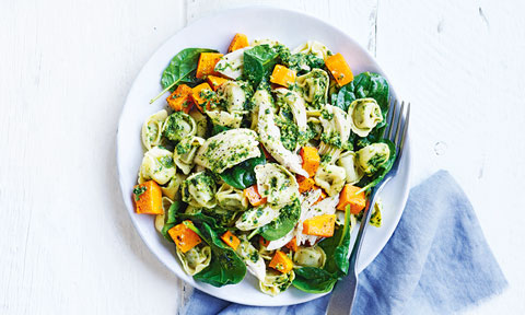 Chicken, pumpkin, spinach and pesto pasta served in a bowl with a fork beside the bowl