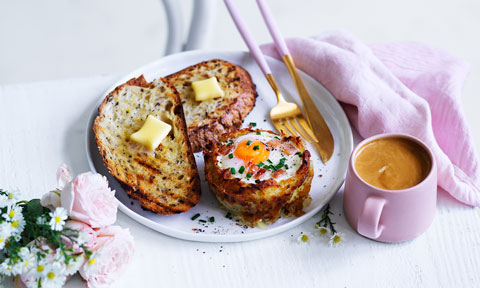 Hash brown egg cup and two slices of toast with butter on a plate with a cup of coffee on the side