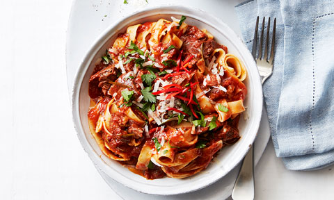 Lamb ragu served in a bowl with coriander and red pepper garnish 