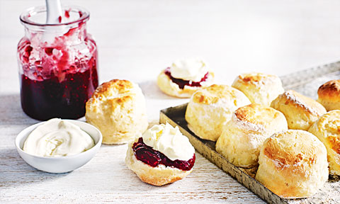 Scones on Baking Tray, one cut in half with Jam and Cream
