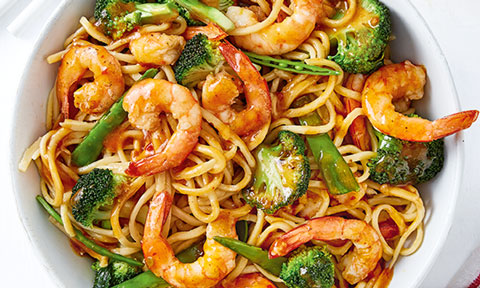 Prawns and noodles tossed with broccoli and snow peas served in a bowl