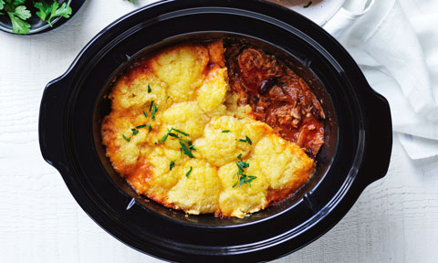 Chilli Pork with Polenta Dumplings in serving dish, topped with flat leaf parsley