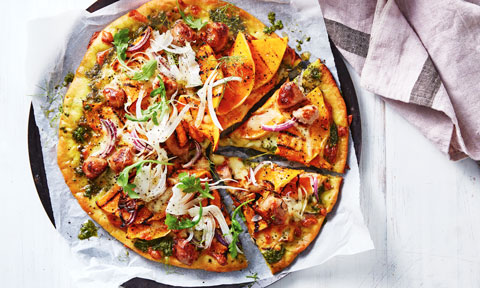 Pumpkin, Sausage and Rocket Pesto Pizza on baking paper, next to a lavender towel
