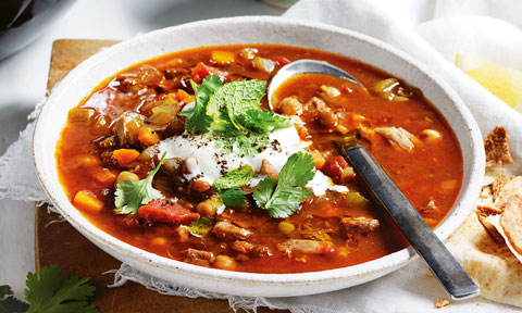 Slow Cooker Spiced Chicken and Chickpea Soup in bowl, garnished with yoghurt and coriander. Served with pita bread