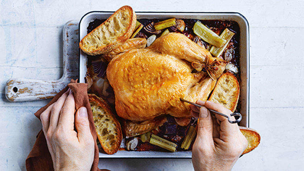 Roast chicken served in baking dish with roasted vegetables