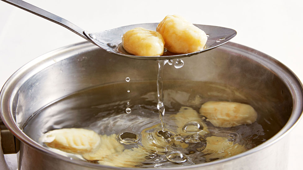 Cooked gnocchi being removed from a pot of water 