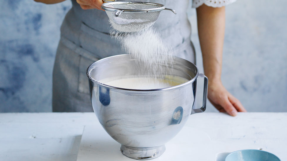 Sifting flour into the cheesecake mix