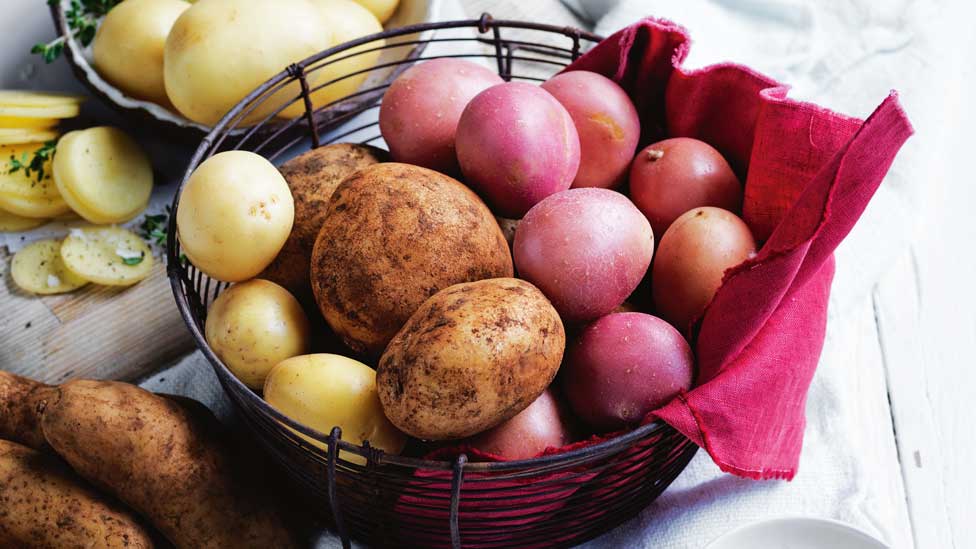 Potatoes in a bowl, with chopped potatoes on the side