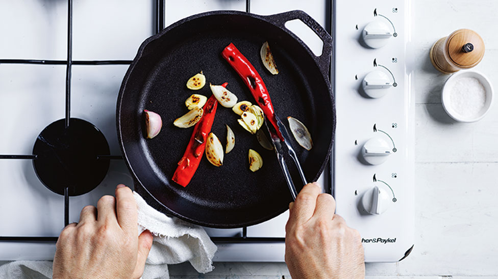 Uncooked pork being placed on a baking tray with veggies