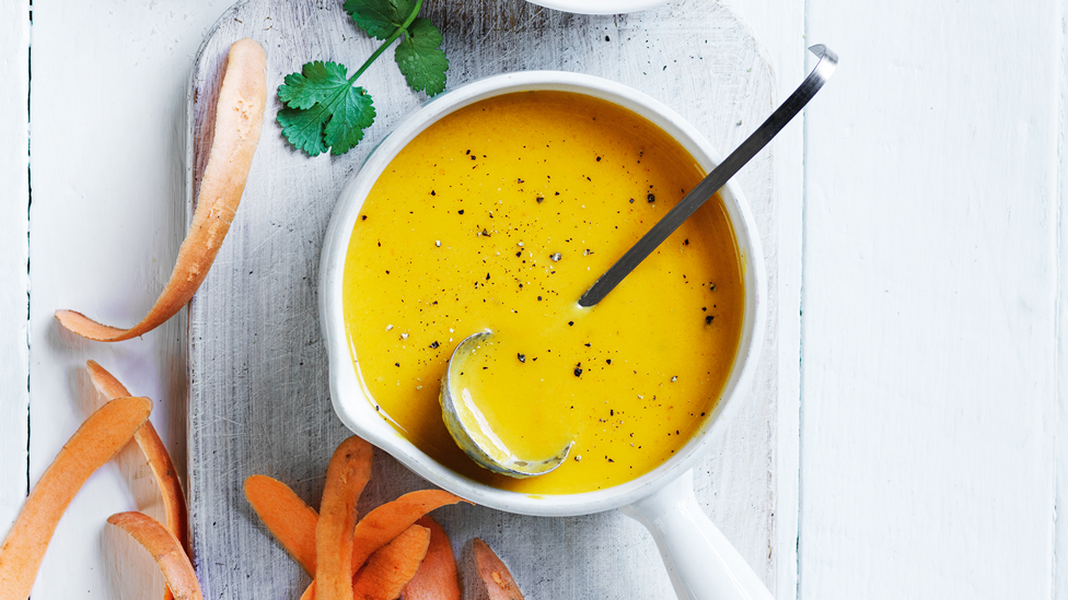 A bowl of veggie peel soup with carrot shavings on the side