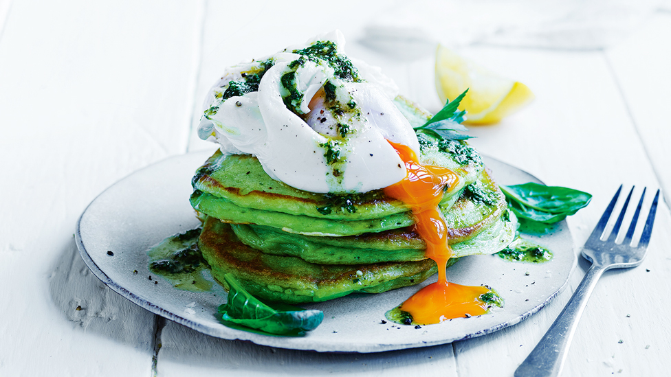 A stack of avocado pancakes with poached egg on top